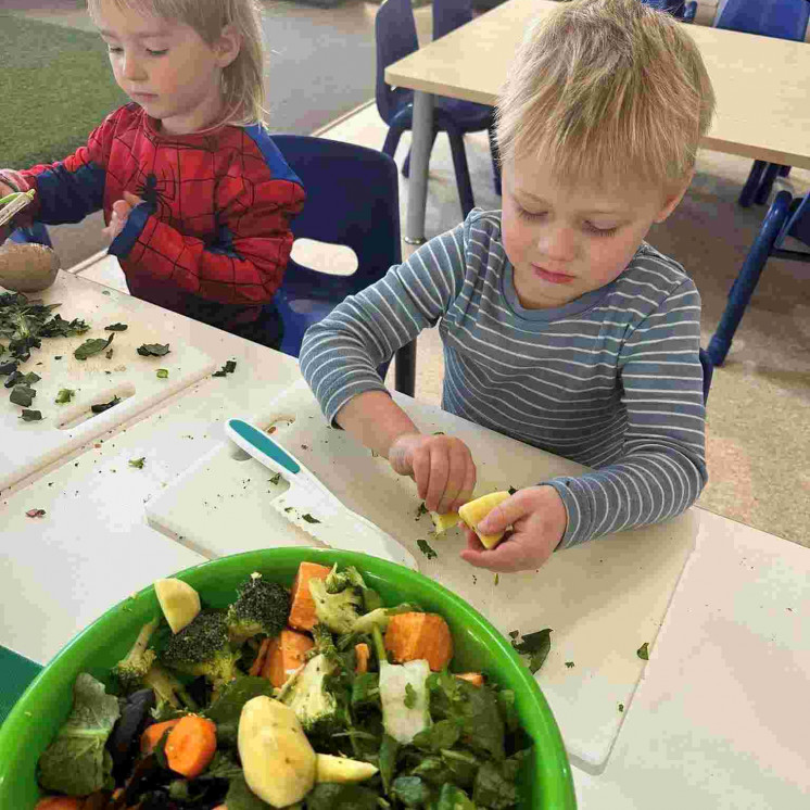 Helping prepare food at Busy Bees Carterton preschool 