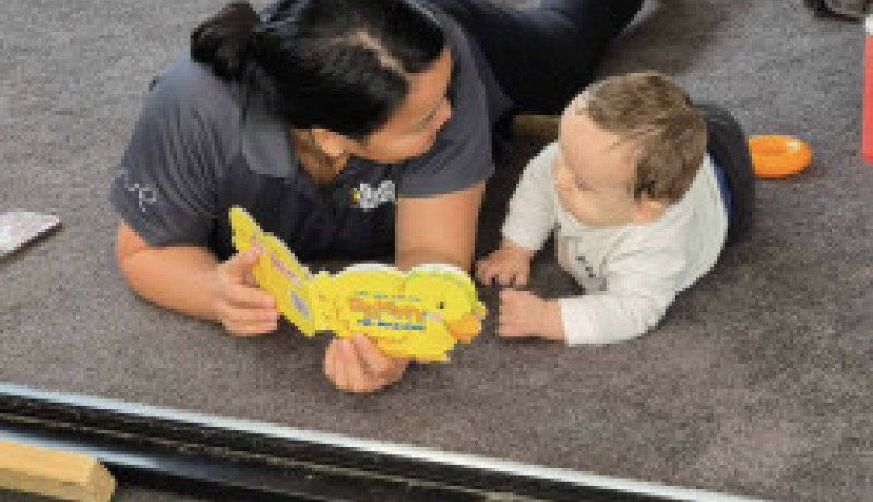 Busy Bees Gladstone Road teacher reading to baby