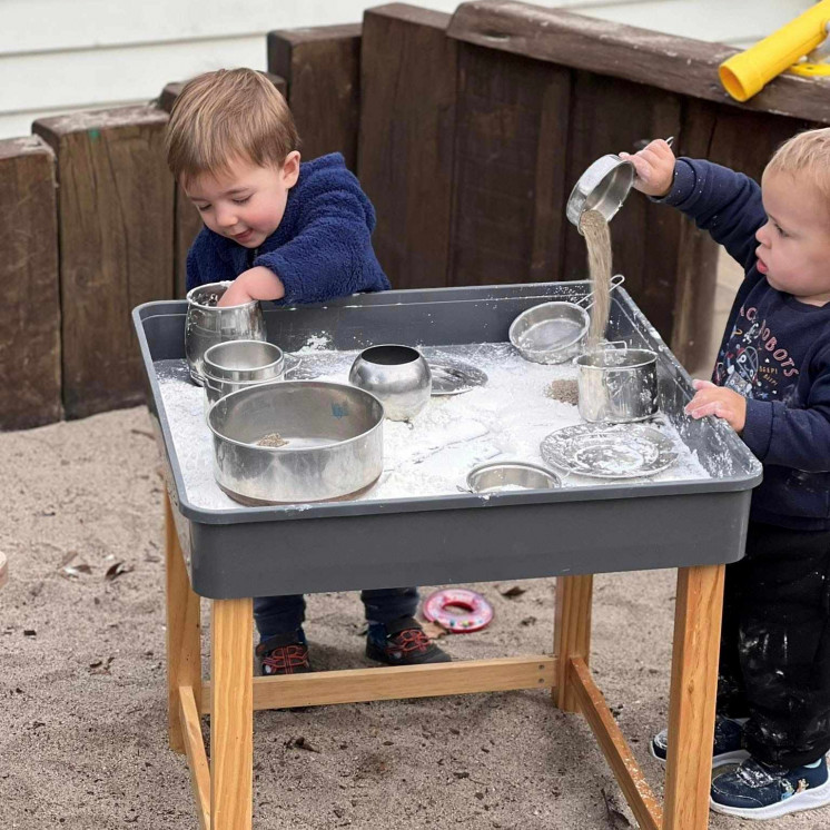 Two friends exploring different sensory materials at Busy Bees Havelock North