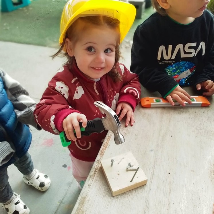 Busy Bees Hobsonville girl building with hammer and nails