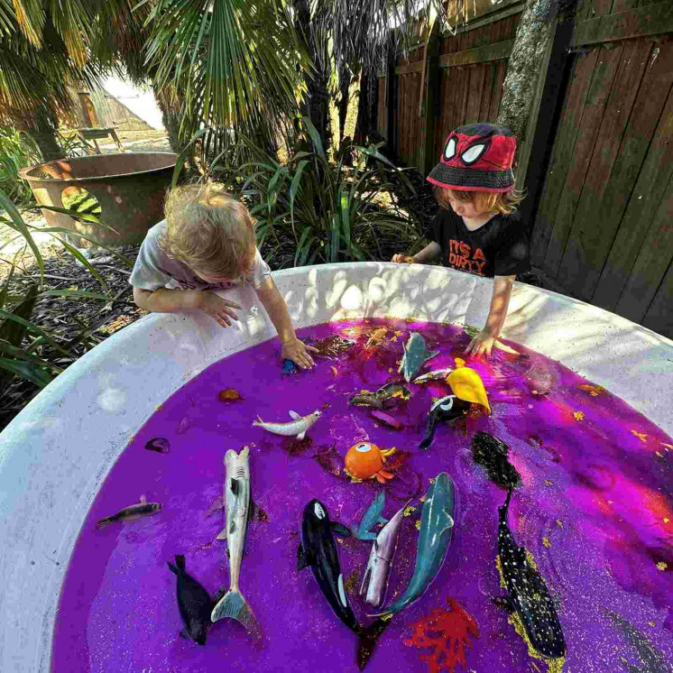 Two friends creating memories with purple water and wildlife creatures at Busy Bees Motueka Childcare