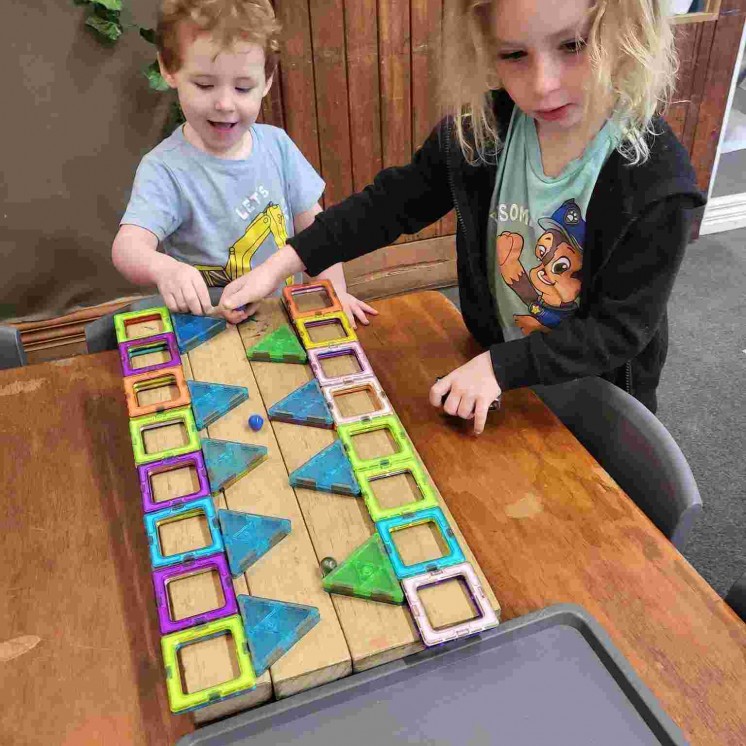 Two friends playing with magnetic shapes at Busy Bees Motueka Childcare