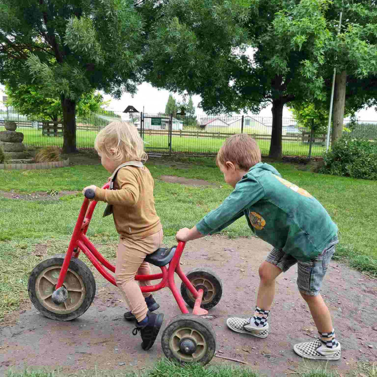 Older boy helping younger boy on the trike at Busy Bees Napier Road