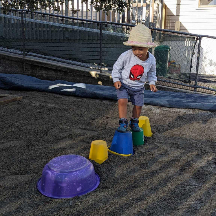 Young boy concentrating on balancing in the sandpit at Busy Bees Ōtāhuhu