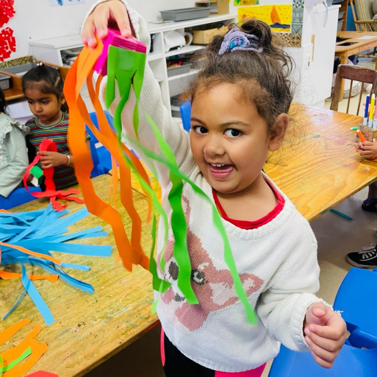 Making colourful creations during learning through play at Busy Bees Ōtāhuhu