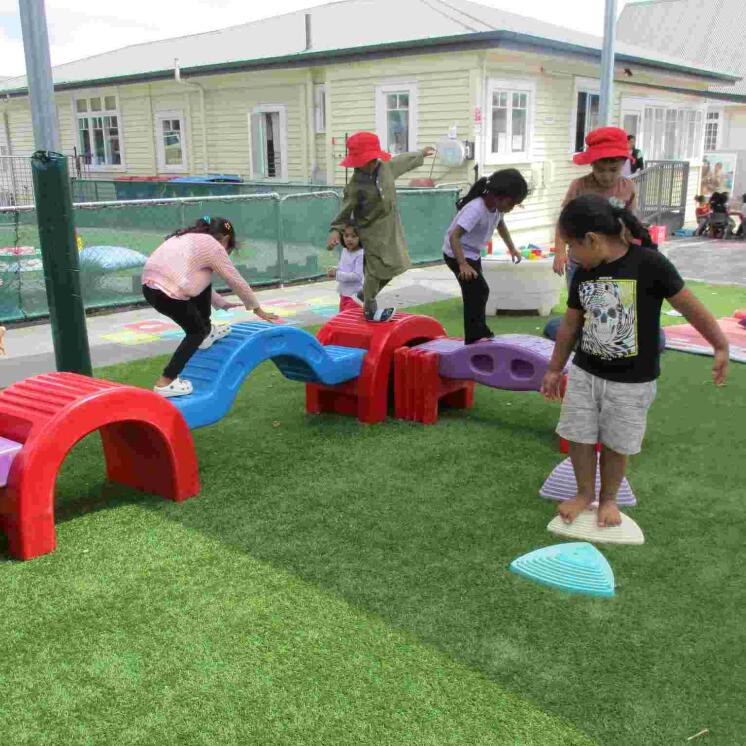 Preschool balancing activity outdoors at Busy Bees Otahuhu