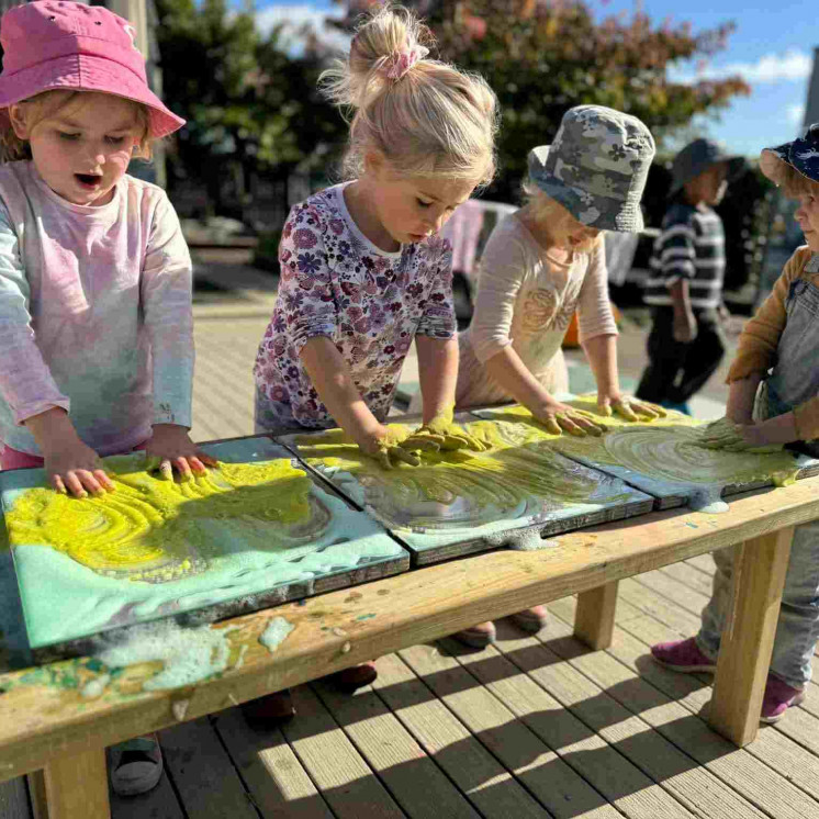 Friends playing outdoors in messy play at Busy Bees Pahiatua