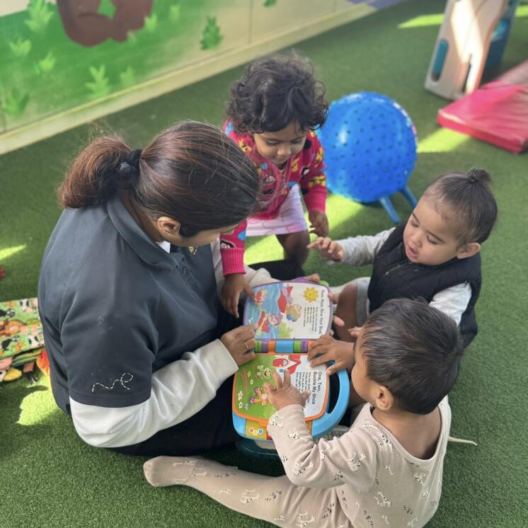 Care moments with baby teacher reading books at Busy Bees Roscommon