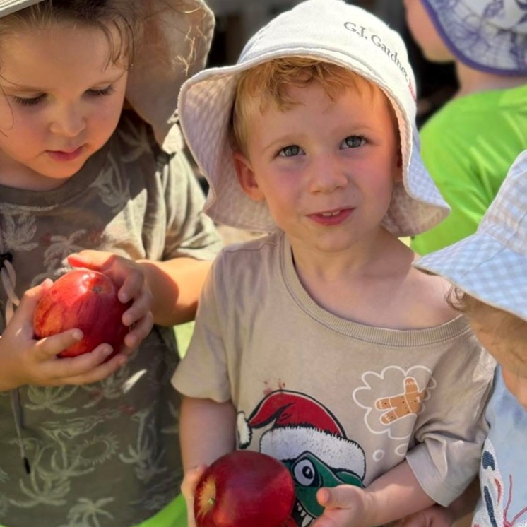 Enjoying fresh apples outdoors 2 boys childcare