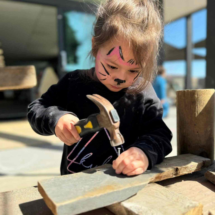 Preschool girl engaged in carpentry at Busy Bees Taupo